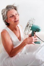 older woman with holding fan for hot flashes